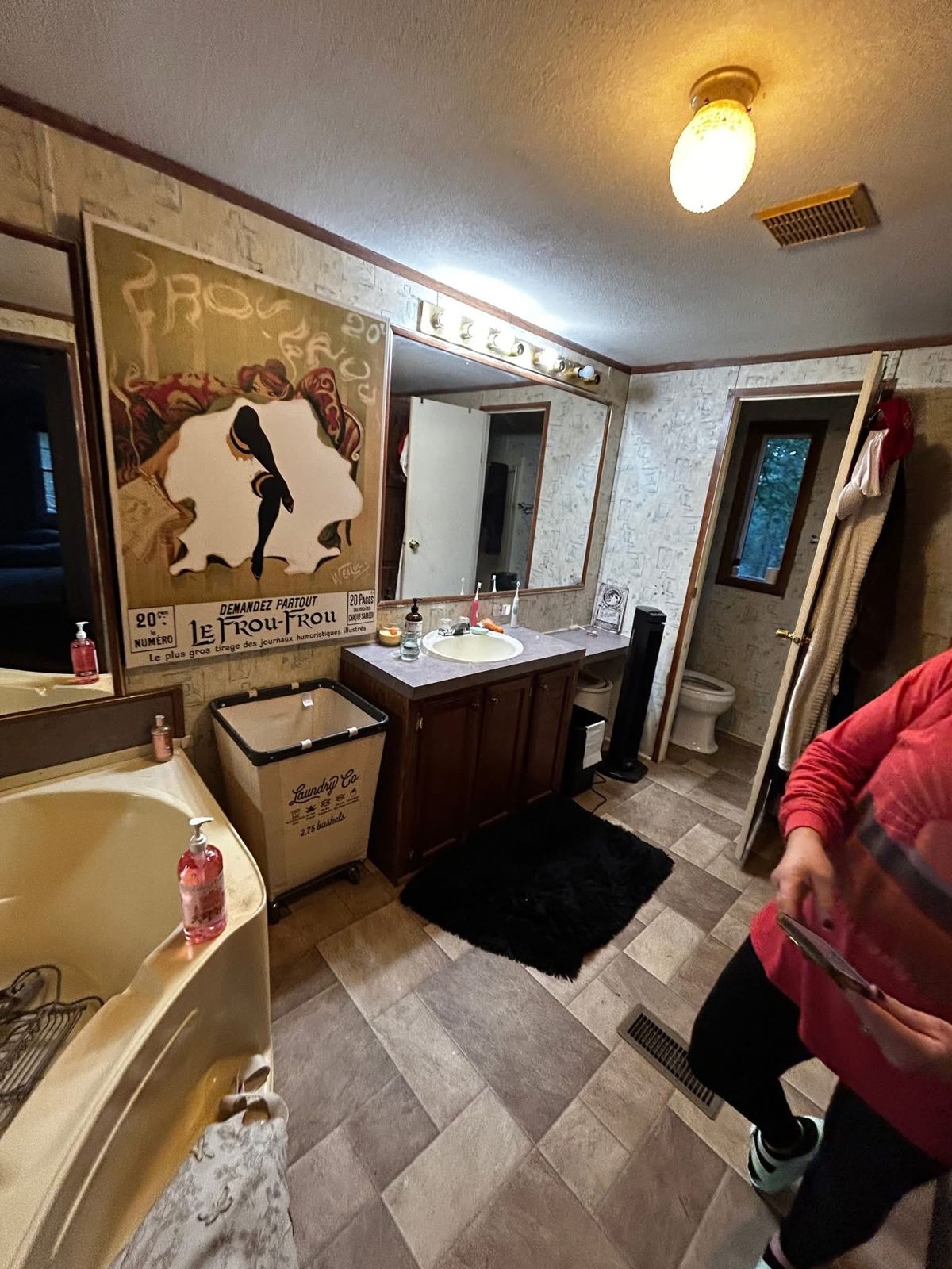 Bathroom before the remodel: patterned wall panels, a cream corner tub, a dark vanity and vinyl floor