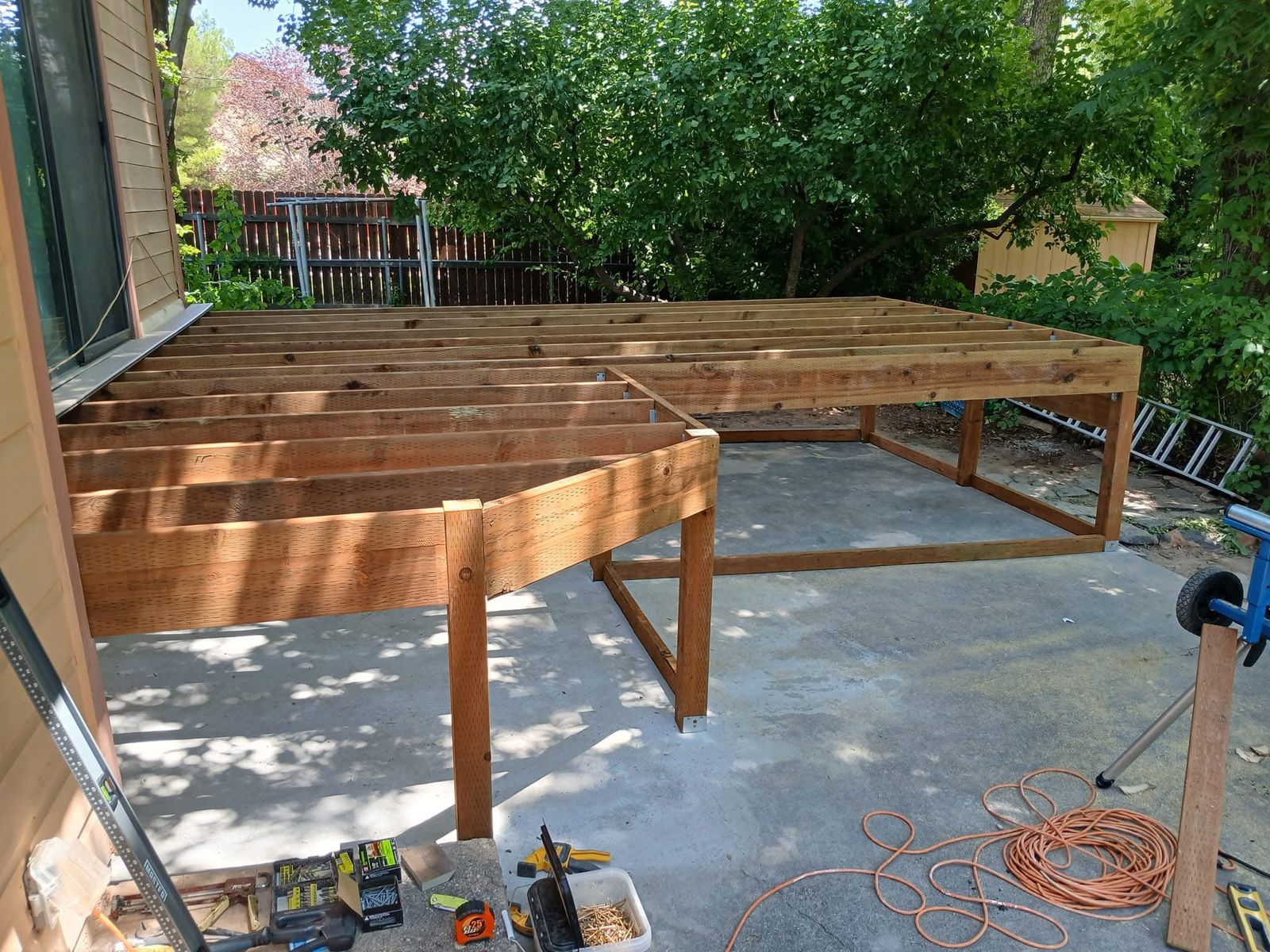 New deck framing with joists, beams and posts on metal brackets, built over a concrete patio