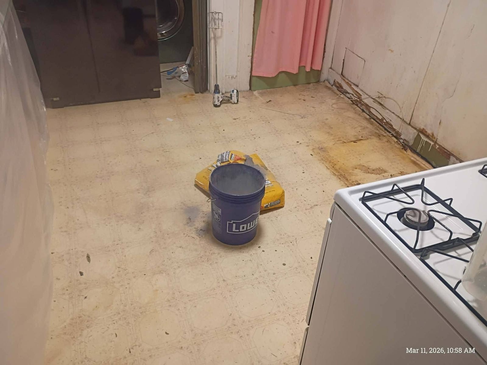 Kitchen floor before: stained vinyl with water damage along the wall
