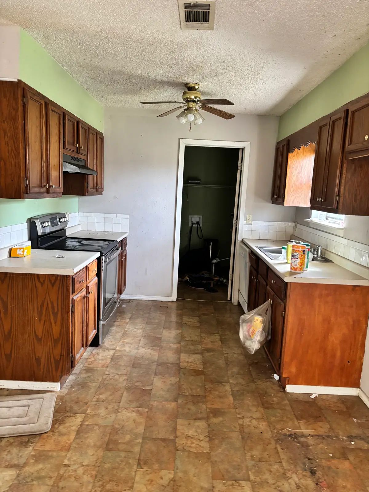 Kitchen before the remodel: dated oak cabinets, green walls and worn vinyl flooring