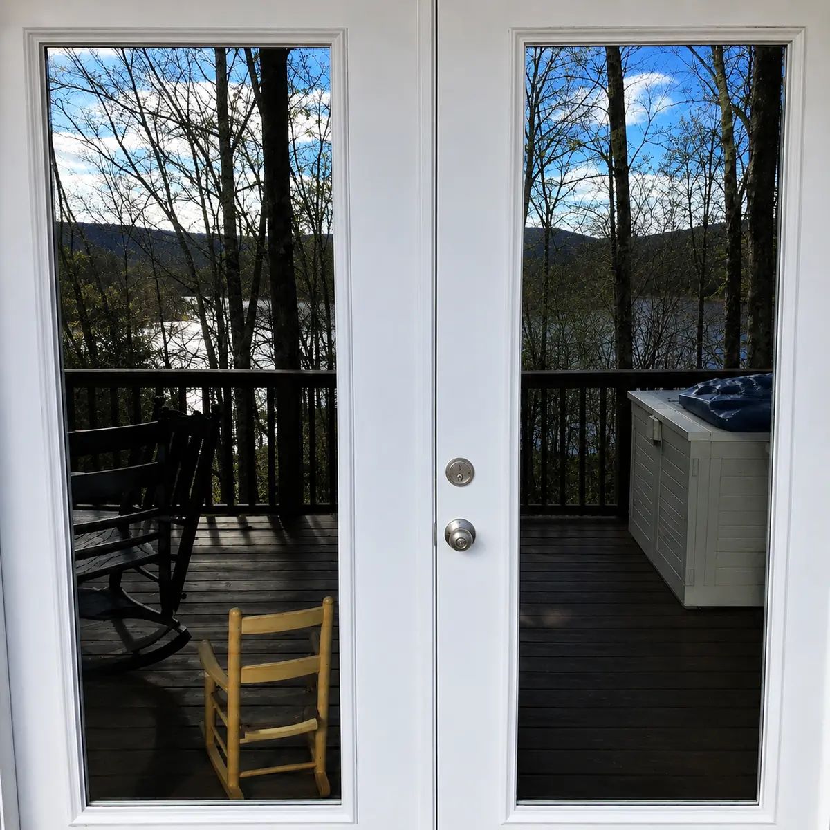 Repainted white French doors opening to a deck with a lake view