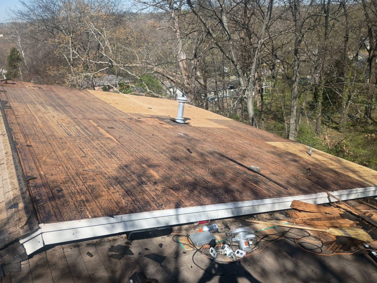 Roof stripped to the decking, with old stained boards and new plywood patched in