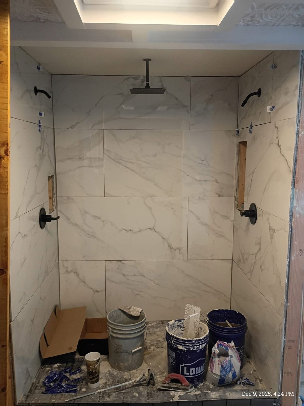 Walk-in shower with large marble-look tile, a ceiling rain head and matte black fixtures